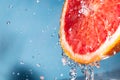 Water drips from half a grapefruit. Splashes and drops fly from a piece of grapefruit symbolizing the brightness and freshness of Royalty Free Stock Photo