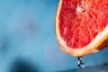 Water drips from half a grapefruit. Splashes and drops fly from a piece of grapefruit symbolizing the brightness and freshness of Royalty Free Stock Photo