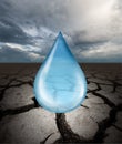 Close up view of water drop against ground cracked with heat and stormy sky Royalty Free Stock Photo