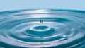 Water drop on blue background. Blue water surface with splash. Clear Waterdrop with circular waves. Splashes closeup. Water splash