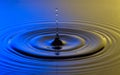 Water drop close up with concentric ripples colourful blue and y Royalty Free Stock Photo