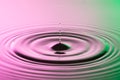 Water drop close up with concentric ripples colourful pink and g Royalty Free Stock Photo