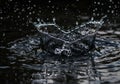 Water Drop Creating Splash Crown with Ripples on Dark Reflective Surface Royalty Free Stock Photo