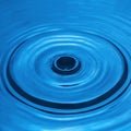 Water drop falling into water making a perfect droplet splash in blue Royalty Free Stock Photo