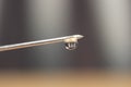 Water drop falling from the syringe needle against grey background Royalty Free Stock Photo