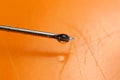 Water drop falling from the syringe needle against orange background Royalty Free Stock Photo