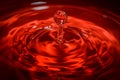 Water drop an waves with red background and reflection Royalty Free Stock Photo
