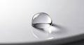 Water droplet rests on a smooth reflective white surface creating a Royalty Free Stock Photo