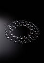 Water droplets arranged in a circular pattern on a glossy black surface create an Royalty Free Stock Photo