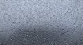 Water droplets cover a smooth glass surface, creating a pattern against a diffuse gra Royalty Free Stock Photo