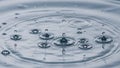 Droplets fall into a smooth rippling surface creating a series of Royalty Free Stock Photo