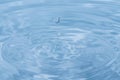 Water droplets falling into clear blue water Royalty Free Stock Photo