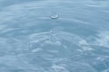 Water droplets falling into clear blue water Royalty Free Stock Photo