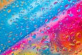 Water drops on a glass above colorful diagonal background of blue, pink, red, orange and yellow colors Royalty Free Stock Photo