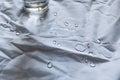 Water droplets and glass shining in light on white fabric drapery with folds Royalty Free Stock Photo