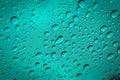 Water droplets scattered on cyan blue glass for background.