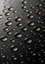 Water droplets on a smooth black surface. The droplets vary in size, creating a pattern Royalty Free Stock Photo