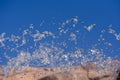 Water droplets spraying from a fountain in abstract design on blue sky and orange background and detail and contrast. Concept Royalty Free Stock Photo