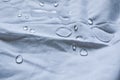 Water droplets on a white fabric drapery with folds shining in light Royalty Free Stock Photo