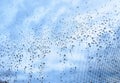 Water droplets on a window with a blue and cloudy sky Royalty Free Stock Photo