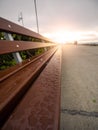 Water droplets on a wooden long bench by a side walk and rising sun with flare in the background. Selective focus. Calm and cool Royalty Free Stock Photo