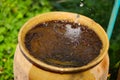 Water dropping from leaking water tap into vintage earthenware jar - save water concept