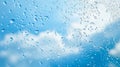 Water drops sliding on glass surface with blurred blue sky and white clouds creating beautiful abstract pattern, perfect Royalty Free Stock Photo