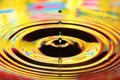 Water drops splash in a glass. Yellow colored ripples, reflections Royalty Free Stock Photo