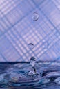 Water drops splashing in front of a blue striped background with reflections of the background in the drops Royalty Free Stock Photo