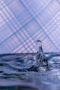 Water drops splashing in front of a blue striped background with reflections of the background in the drops Royalty Free Stock Photo