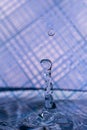 water drops splashing in front of a blue striped background with reflections of the background in the drops Royalty Free Stock Photo