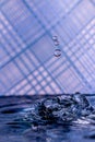 Water drops splashing in front of a blue striped background with reflections of the background in the drops Royalty Free Stock Photo