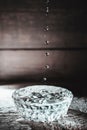 Water drops splashing into glass bowl of water