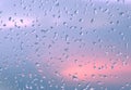 Water drops on transparent glass. Raindrops on a window against a stormy sunset sky in dark blue with red gaps. Mood after Royalty Free Stock Photo