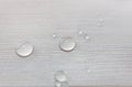 Water drops on white wooden surface made from larch wood covering by oil with wax.