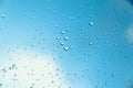 Water drops on the window, blue sky and clouds in the blurry background Royalty Free Stock Photo