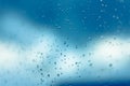 Water drops on the window, blue sky and clouds in the blurry background Royalty Free Stock Photo