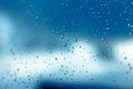 Water drops on the window, blue sky and clouds in the blurry background Royalty Free Stock Photo