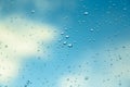 Water drops on the window, blue sky and clouds in the blurry background Royalty Free Stock Photo