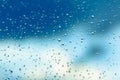 Water drops on the window, blue sky and clouds in the blurry background Royalty Free Stock Photo