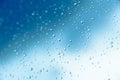 Water drops on the window, blue sky and clouds in the blurry background Royalty Free Stock Photo