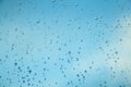 Water drops on the window, blue sky and clouds in the blurry background Royalty Free Stock Photo