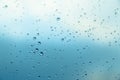 Water drops on the window, blue sky and clouds in the blurry background Royalty Free Stock Photo