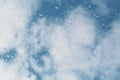 Water drops on a window glass, a blue cloudy sky at the background.