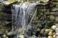 Water falling over stone wall in garden setting Royalty Free Stock Photo