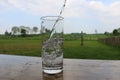 Fresh water falls into a glass which stands on a table in the garden Royalty Free Stock Photo