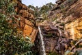 the water falls into a small waterfall below a large rocky outcropping Royalty Free Stock Photo