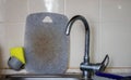 Water faucet and gray cutting board in the background. Dirty cutting board near the sink, unwashed dishes after cooking Royalty Free Stock Photo