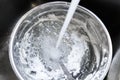 Water from faucet splashing into a stainless steel bowl and spoon thats have just been used to whip egg whites - sitting in a stai Royalty Free Stock Photo