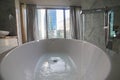 Water filling in modern bathtub in bathroom interior - modern glass buildings on a background Royalty Free Stock Photo